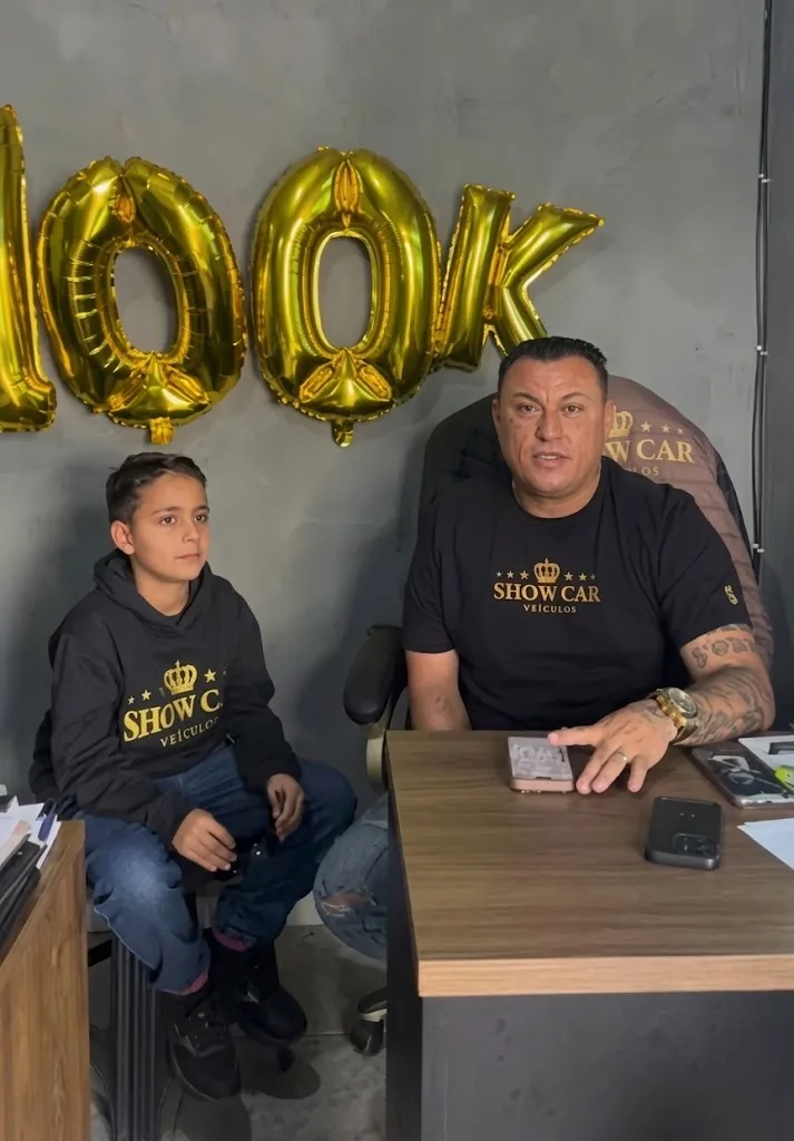Diogo e o filho no escritório da Show Car comemorando 100 mil seguidores com balões dourados