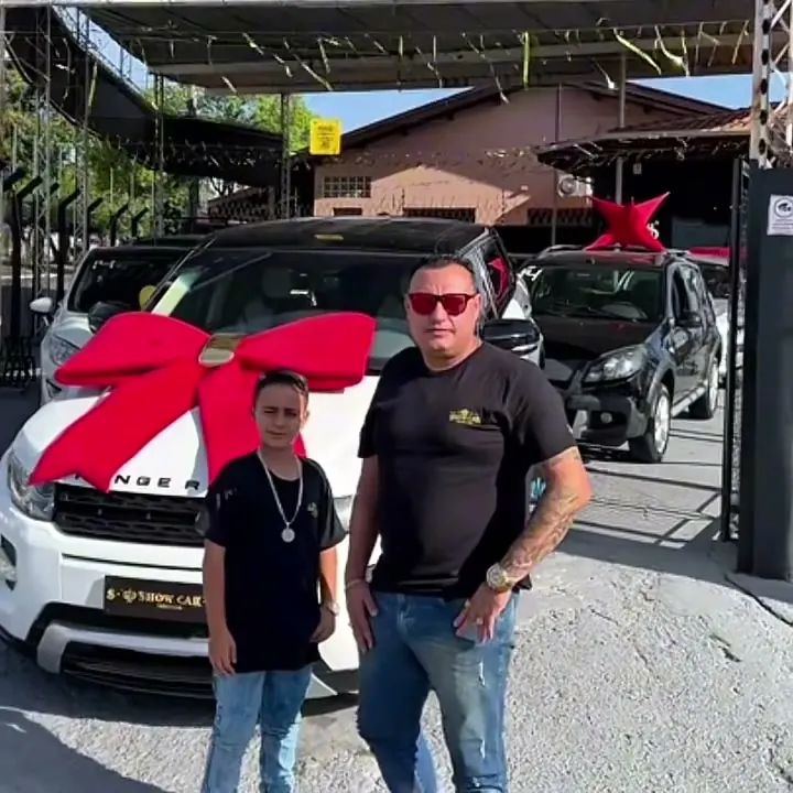 Diogo e o filho, a dupla da Show Car, em frente a um carro com laço vermelho